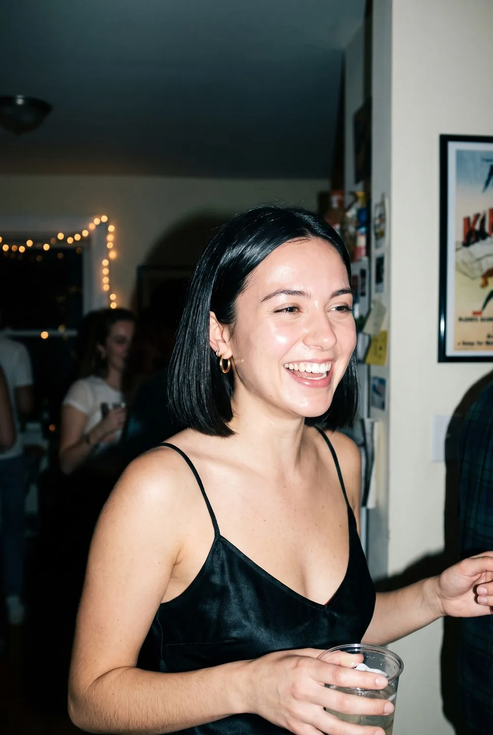 Direct-flash party portrait of a woman with a dark bob and gold hoops, in the style of a Canon G7X compact camera